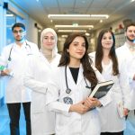 Group of diverse medical students wearing lab coats in university corridor, representing future healthcare professionals.